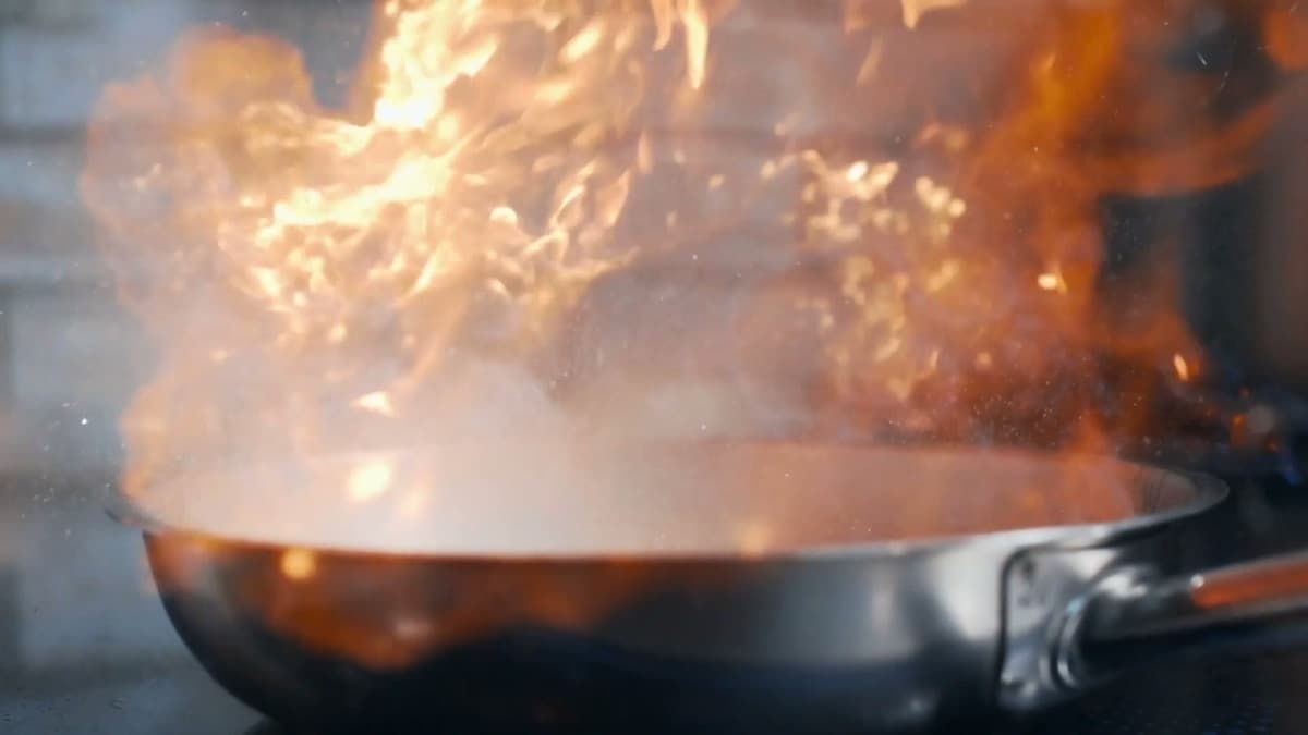 A pan fire flaring on a stovetop
